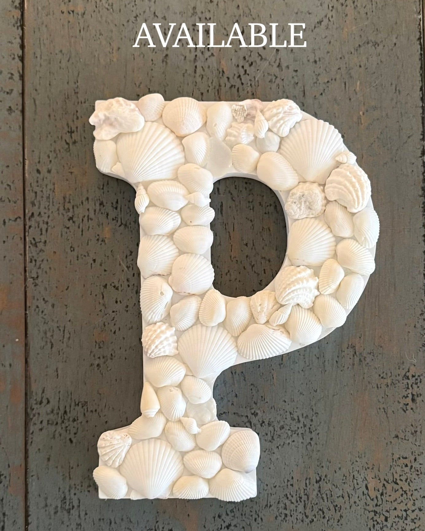 Decorative letter 'P' made of white shells on a textured dark background with 'AVAILABLE' text.