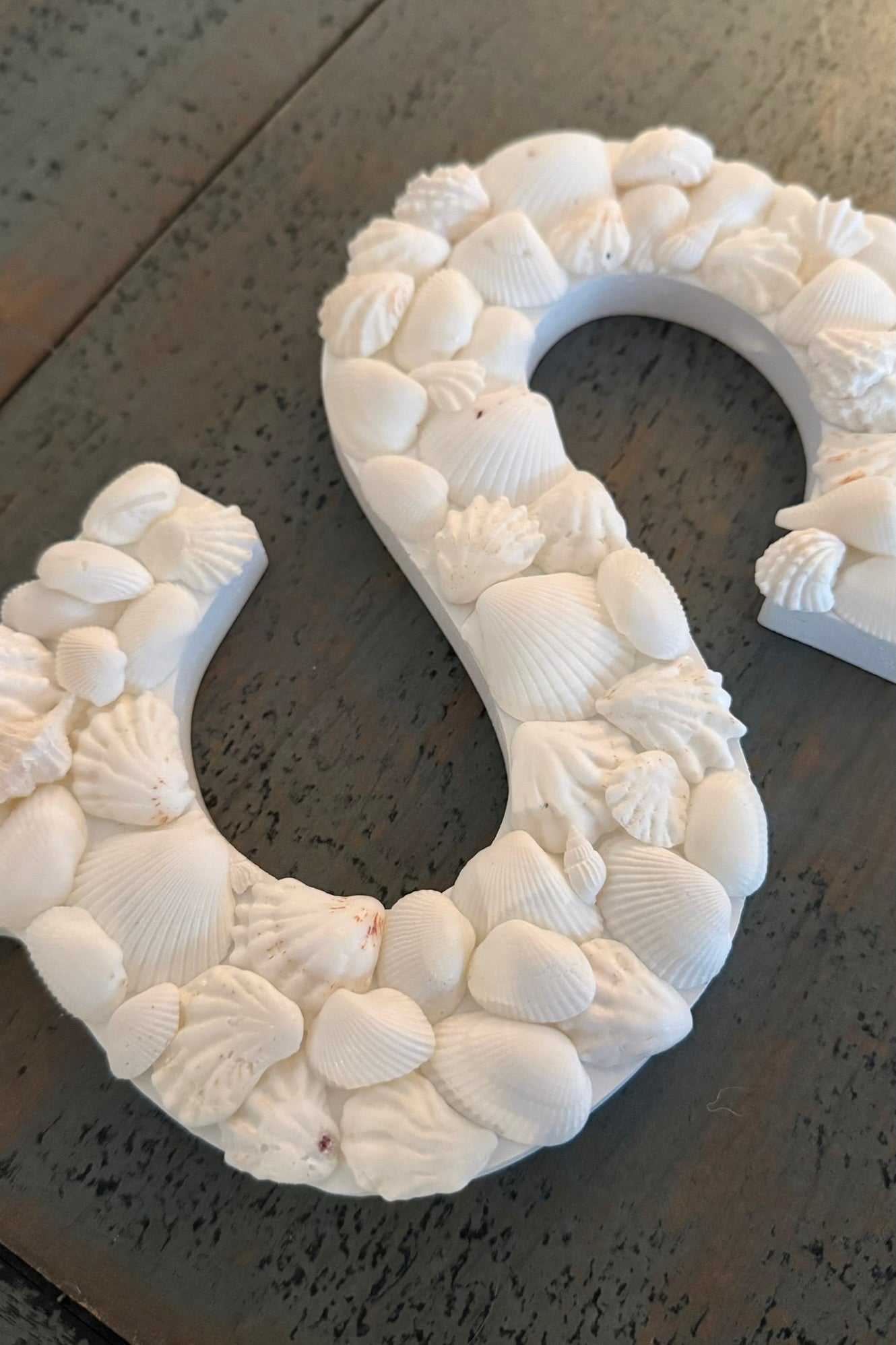 Decorative number 'S' made of seashells on a dark surface