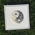Framed artwork of a yin yang symbol on grass