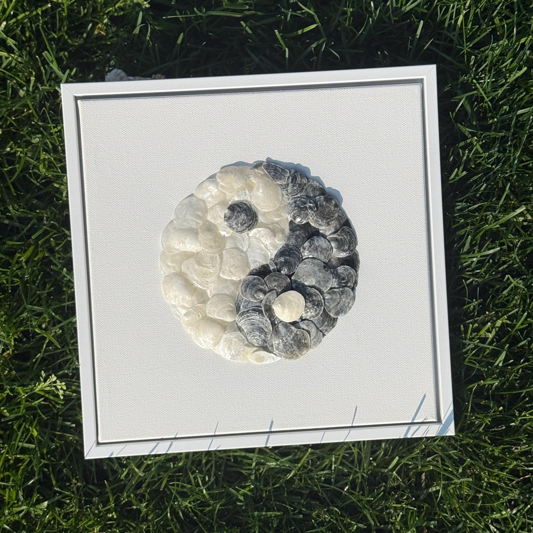 Framed artwork of a yin yang symbol on grass