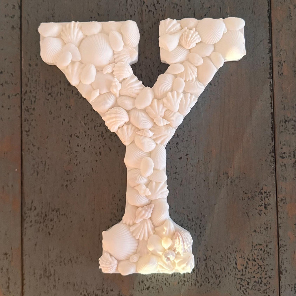 Decorative letter 'Y' made of seashells on a textured metal background