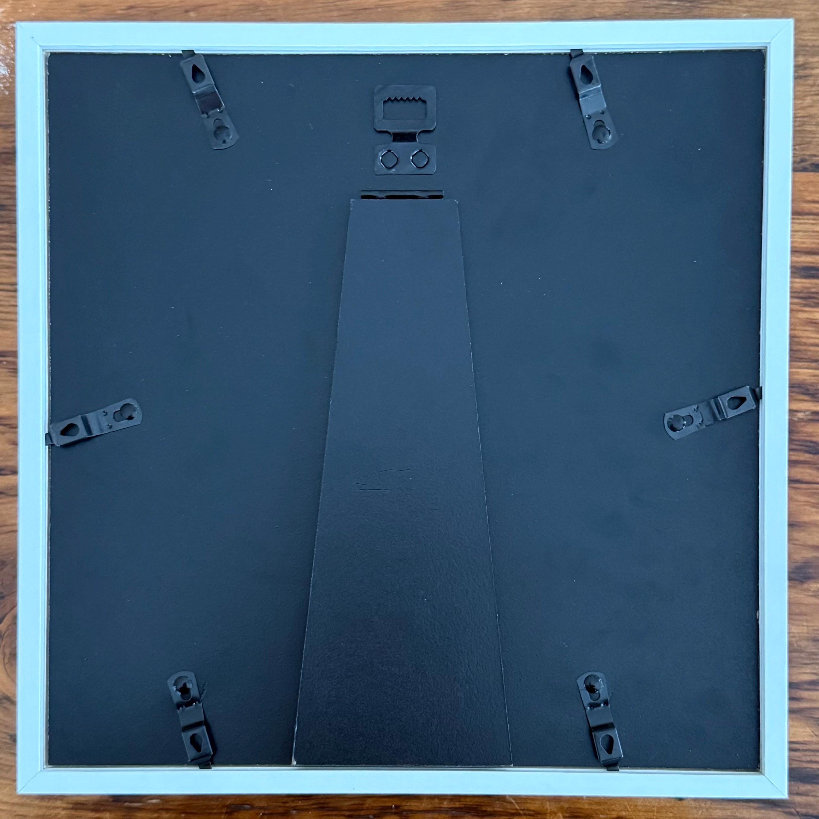 Back of a picture frame with mounting hardware on a wooden surface